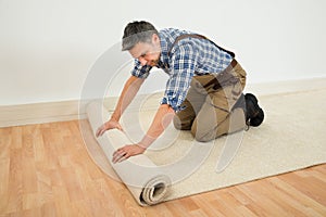 Worker unrolling carpet on floor