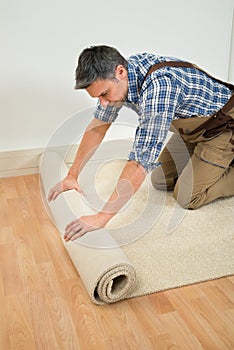 Worker unrolling carpet on floor