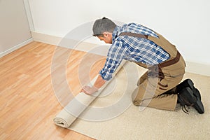 Worker unrolling carpet on floor photo