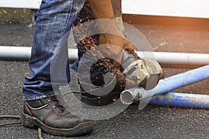 Worker use electric wheel grinding on steel pipe for cut. Sparks from the grinding wheel metalworking. Industry concept