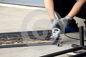 Worker use hand grinder to grinding the square metal pipe.