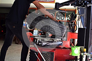 Worker use tire changer matchine in tire car shop.