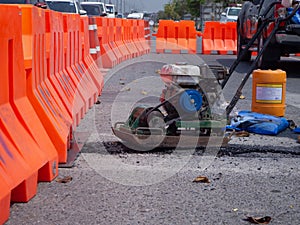 Worker use vibratory plate compactor compacting asphalt at road