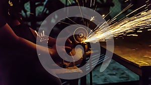 the worker uses cutting machine to cut metal, focus on flash light line of sharp spark,in low Light