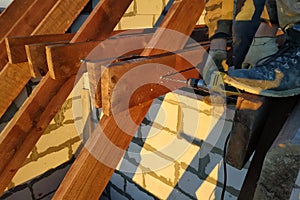 The worker uses a drill in the construction of the roof