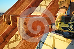 The worker uses a drill in the construction of the roof