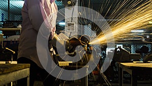 worker uses grinding cut metal, focus on flash light line of sharp spark,in low light