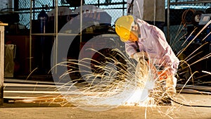 worker uses grinding cut metal, focus on flash light line of sharp spark,in low light