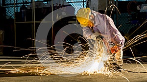 Worker uses grinding cut metal, focus on flash light line of sharp spark,in low light