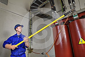 Worker uses insulating stick to earth grounding transformer. photo