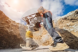 Worker uses a portable vibration rammer at construction of a power transmission substation