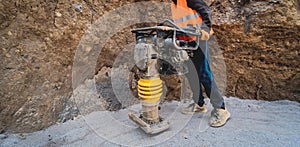 Worker uses a portable vibration rammer at construction of a power transmission substation