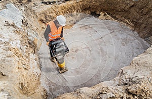 Worker uses a portable vibration rammer at construction of a power transmission substation