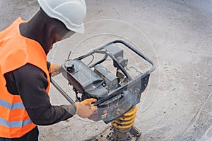 Worker uses a portable vibration rammer at construction of a power transmission substation