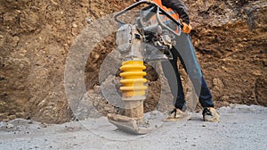 Worker uses a portable vibration rammer at construction of a power transmission substation