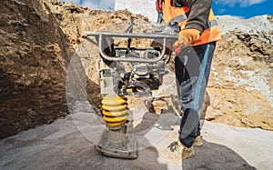 Worker uses a portable vibration rammer at construction of a power transmission substation