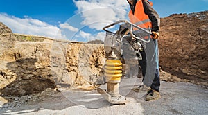 Worker uses a portable vibration rammer at construction of a power transmission substation