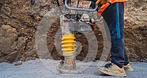 Worker uses a portable vibration rammer at construction of a power transmission substation