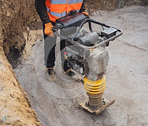 Worker uses a portable vibration rammer at construction of a power transmission substation