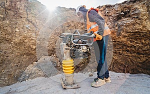 Worker uses a portable vibration rammer at construction of a power transmission substation