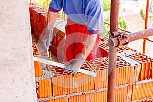 Worker uses a spirit level to control wall made of red blocks