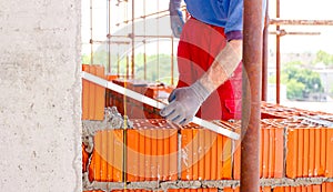 Worker uses a spirit level to control wall made of red blocks