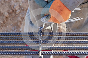 A worker uses steel tying wire to fasten steel rods to reinforcement bars. Close-up. Reinforced concrete structures - knitting of