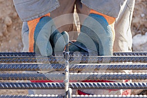 A worker uses steel tying wire to fasten steel rods to reinforcement bars. Close-up. Reinforced concrete structures - knitting of