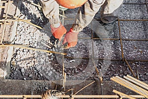 A worker uses steel tying wire to fasten steel rods to reinforcement bars. Reinforced concrete structures - knitting of a metal