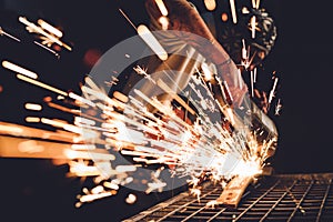 Worker Using Angle Grinder in Factory and throwing sparks.