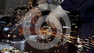 Worker using angle grinder in factory and throwing sparks. Frame. Man wearing protective uniform and cutting metal with