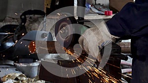 Worker using angle grinder in factory and throwing sparks. Frame. Man wearing protective uniform and cutting metal with