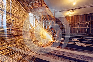 Worker is using angle grinder with fountain of sparks in apartment that is under construction, remodeling, renovation