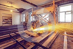 Worker is using angle grinder with fountain of sparks in apartment that is under construction, remodeling, renovation