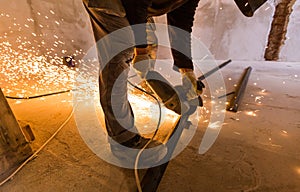 Worker is using angle grinder with fountain of sparks in apartment that is under construction, remodeling, renovation