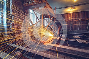 Worker is using angle grinder with fountain of sparks in apartment that is under construction, remodeling, renovation