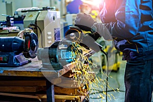 Worker using an angle grinder for sharpening a metal