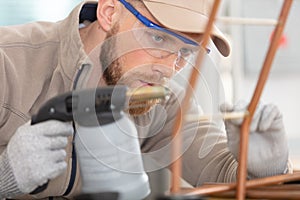 worker using blowtorch for soldering copper