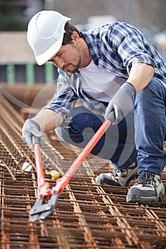 worker using bolt croppers on metal rebars