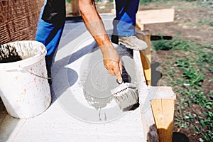 worker using brush and primer for hydroisolating and waterproofing house