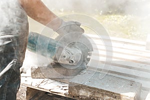 Worker using circular saw for cutting concrete block for road