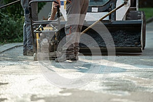Worker using compactor in roadwork photo