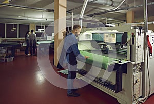 Worker using a cutting machine in a workshop of a footwear manufacturing factory