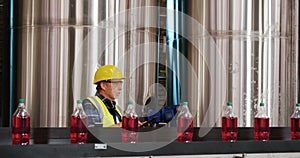Worker using digital tablet in bottle factory