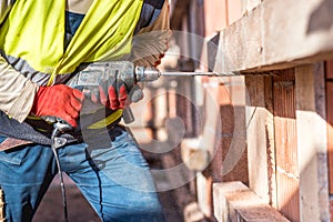 Worker using a drilling power tool on construction site photo