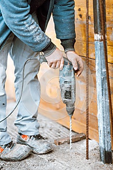 Worker using a rotary power tool on construction site and creating holes in concrete