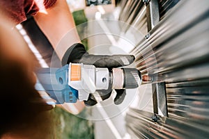 worker using electrical cord screwdriver for fastening screws into metal fence