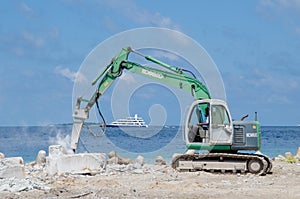 Worker using excavator at construction site on shore of ocean