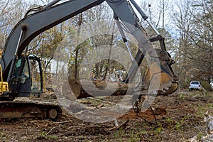 A worker is using an excavator to remove trees in forest a make way for house construction.