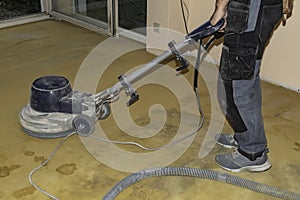 A worker using a grinder to prepare the floor for a new flooring